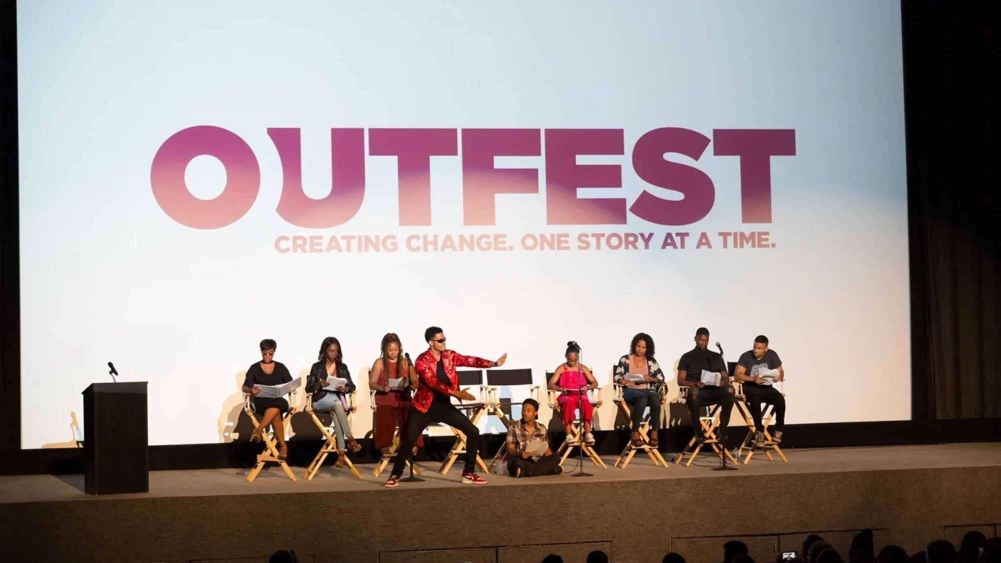 Several people onstage reading form scripts at Outfest