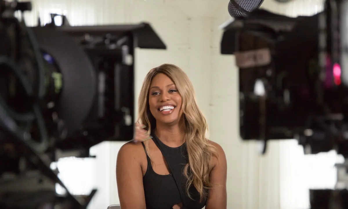 Laverne Cox smiles, framed by two cameras