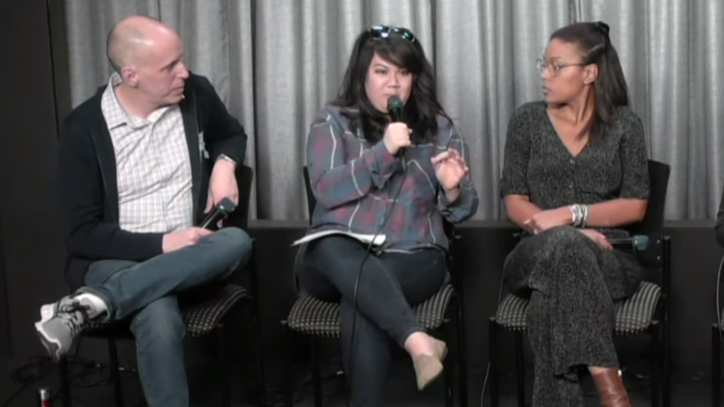 Three people sitting and speaking out of a microphone