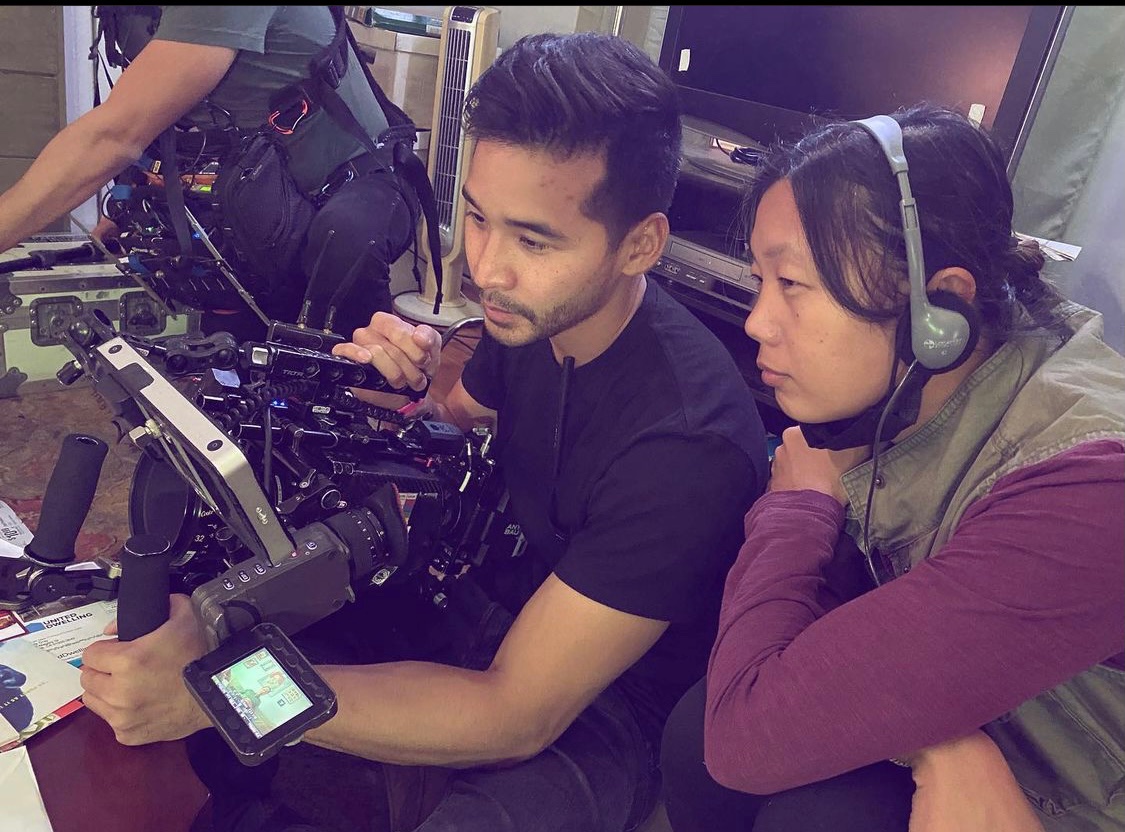Two people looking into the monitor of a camera on set