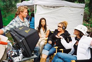 Four cast on set around a monitor